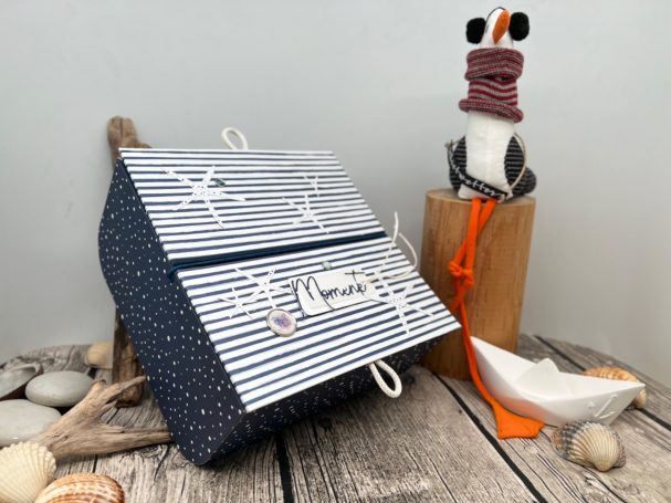 Blau-weiß gestreifte Box mit maritimen Motiven neben einer dekorativen Möwe.